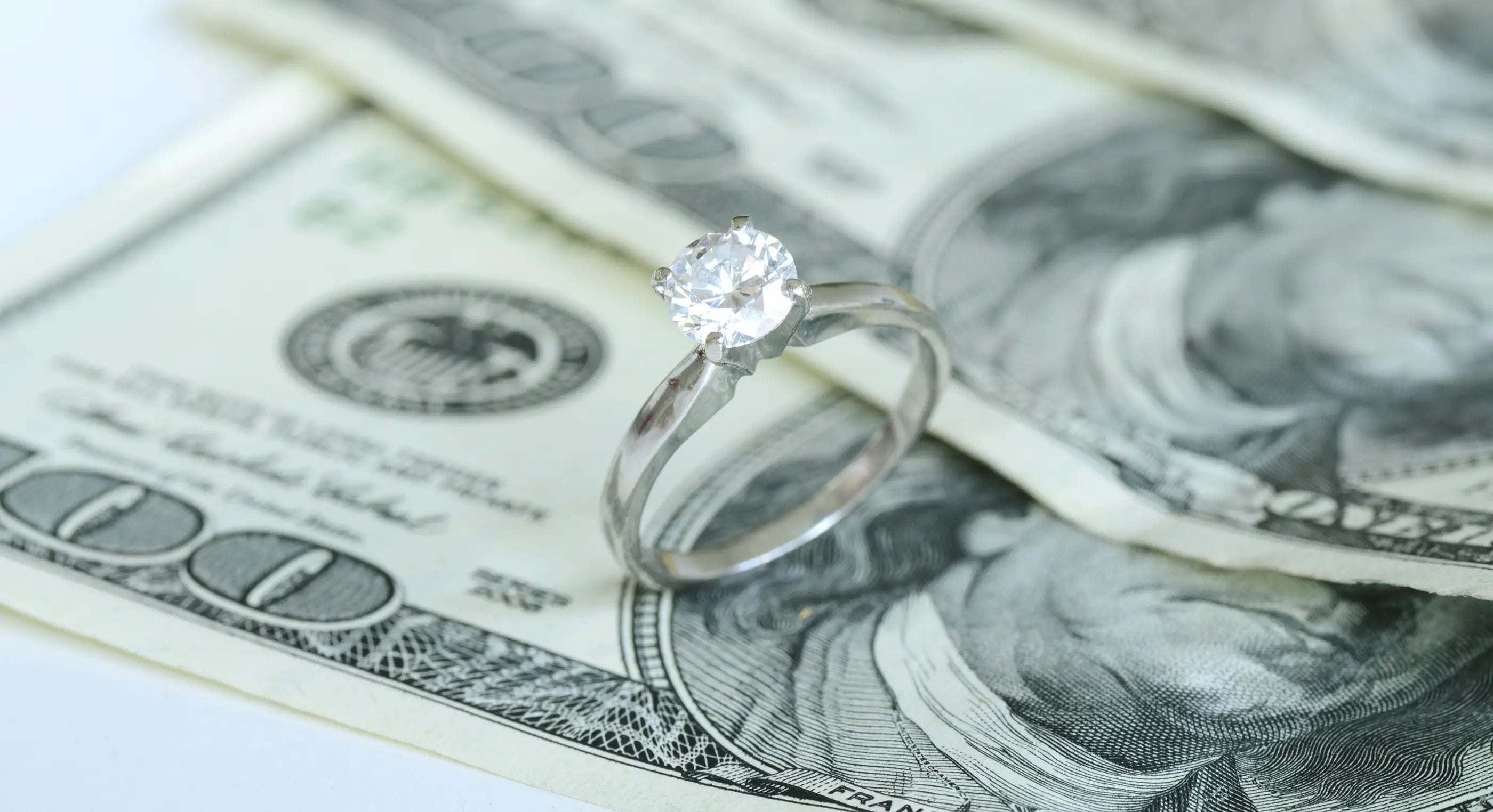 close-up of diamond ring sitting on top of cash