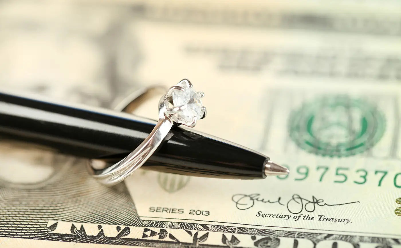 ballpoint pen and diamond ring sitting on top of cash